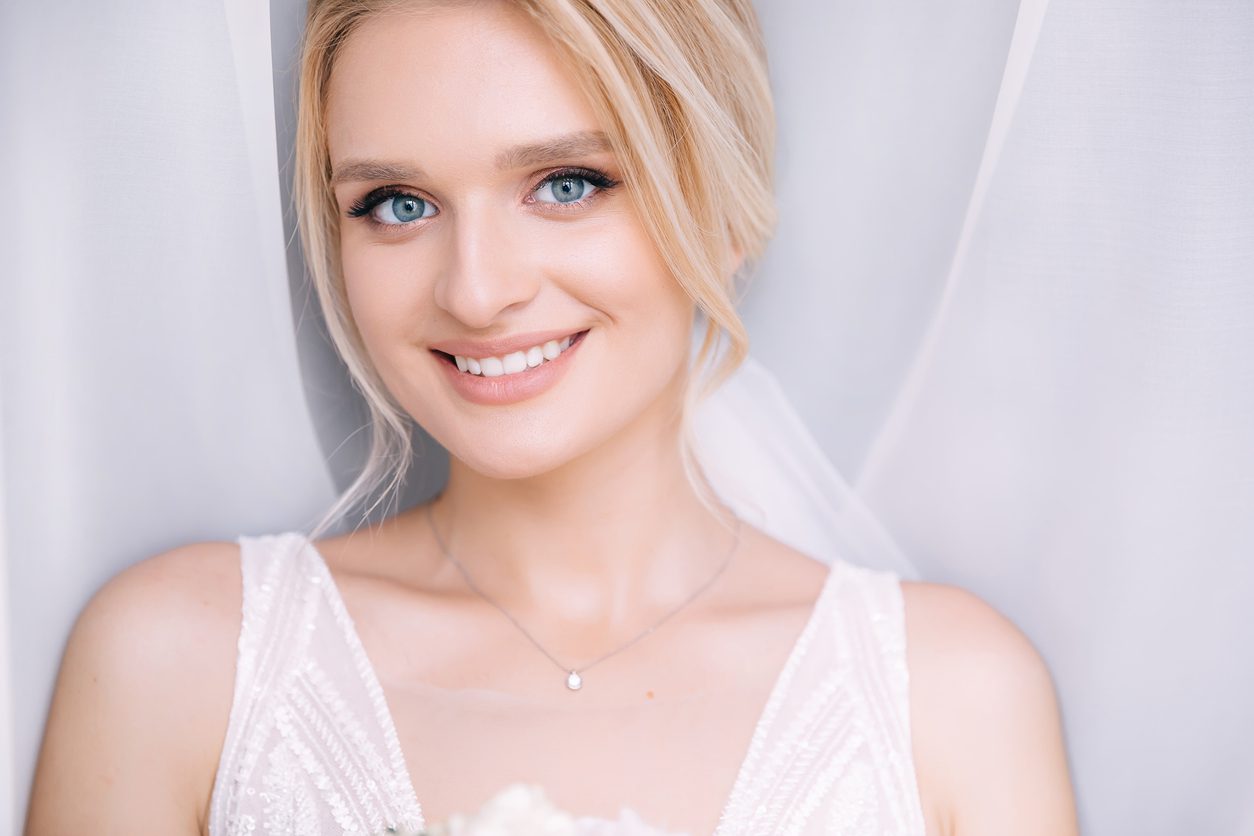 gorgeous happy luxurious stylish blonde bride near the window on a white curtain background.