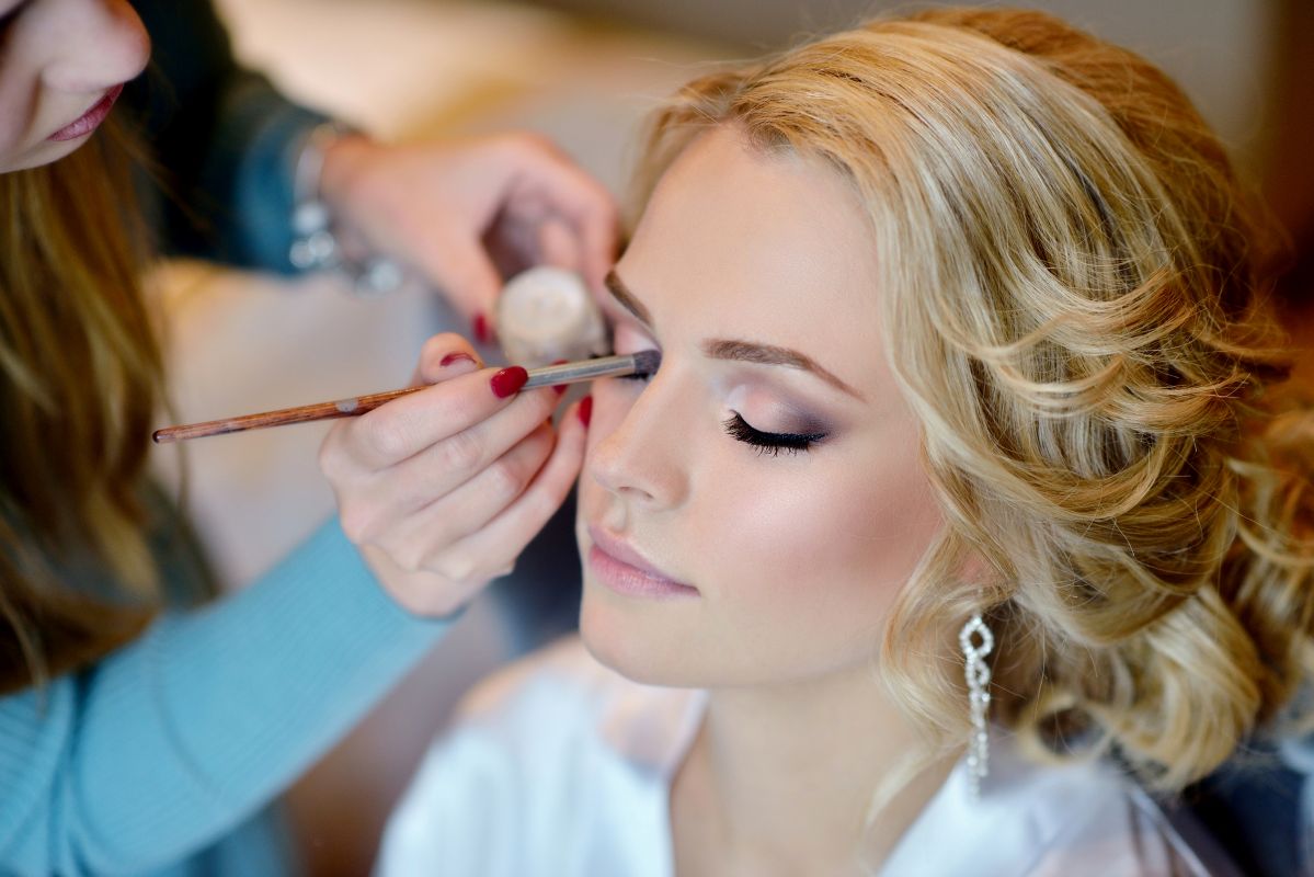 Makeup artist applying eye makeup to bride